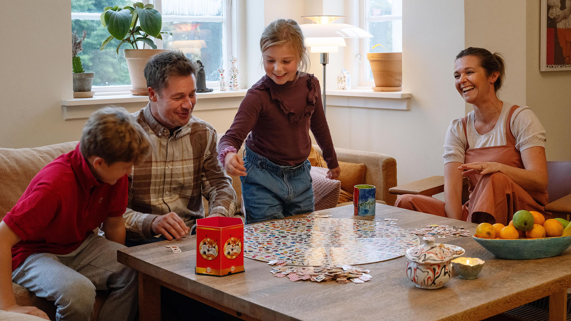 Familie spiller braetspil i stuen